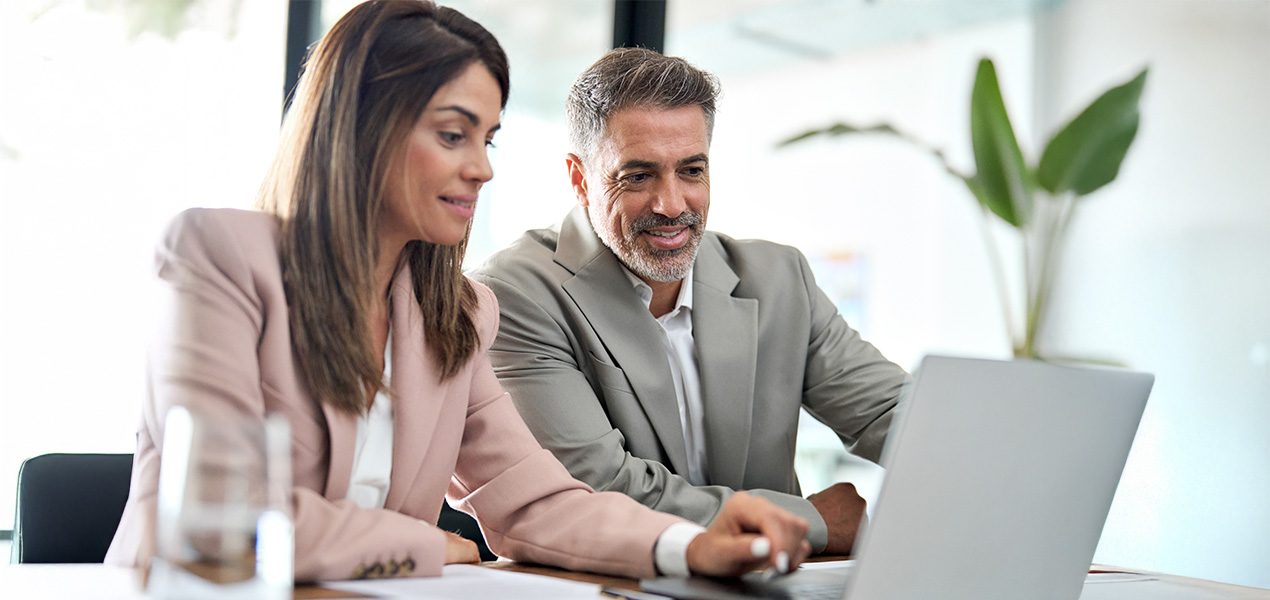 Man and woman in an office analyzing information on a laptop.